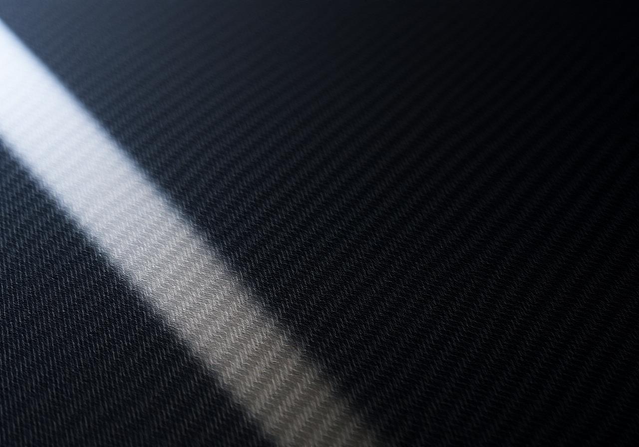 Macro photograph of a black carbon fiber twill weave under a clear gloss finish
