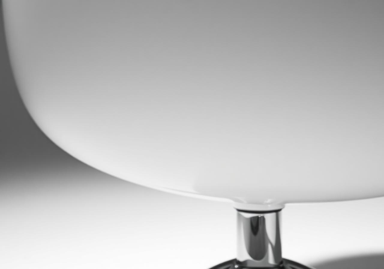 Macro detail of the curved fiberglass shell and chrome stem of a Saarinen Womb chair